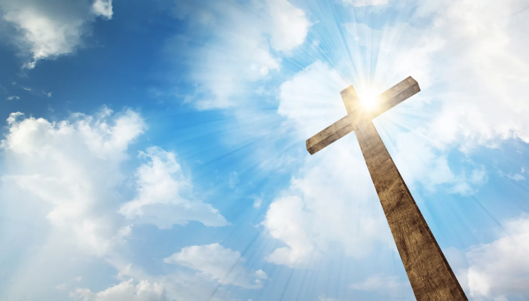 A Wooden Christian Cross With Bright Sun And Clouds